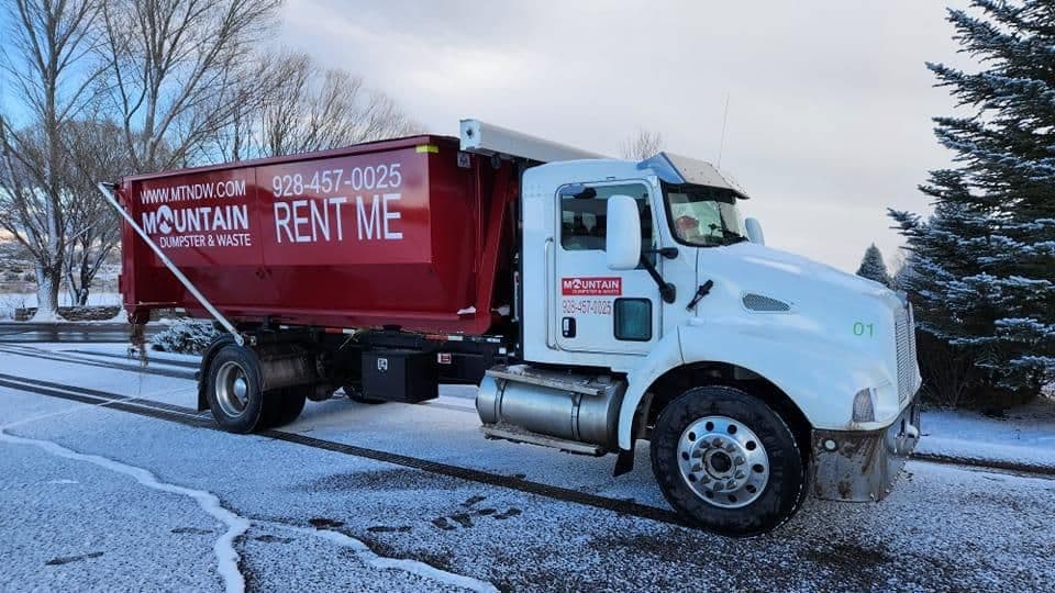 Mountain Dumpsters & Waste truck parked on a snowy road, promoting rental services.