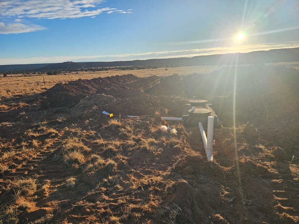 Sunrise over a construction site with excavation and pipes on a rural landscape.