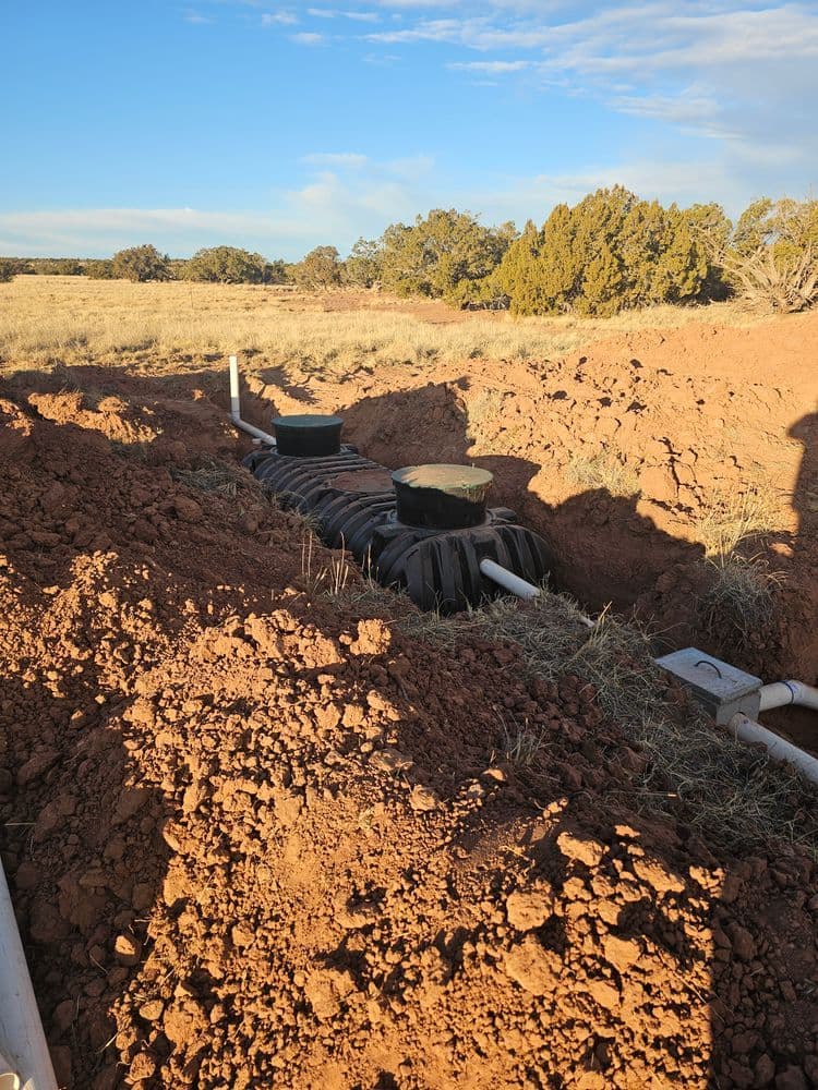 Installation of a septic system in a rural area featuring excavation and tanks.