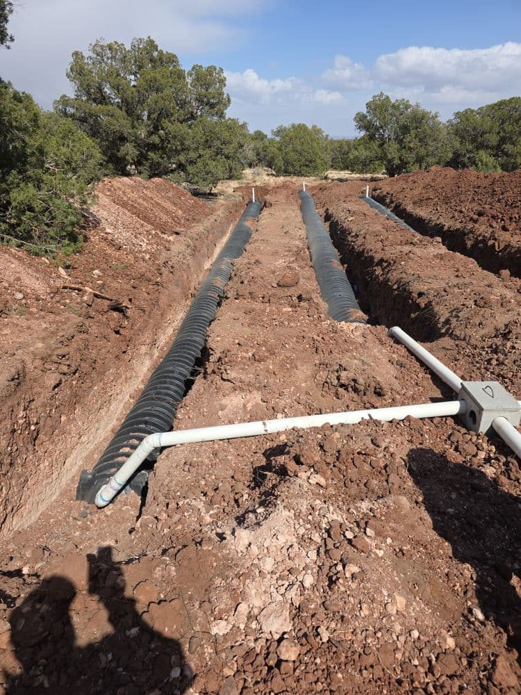Trenches with drainage pipes in a rocky landscape for effective water management.