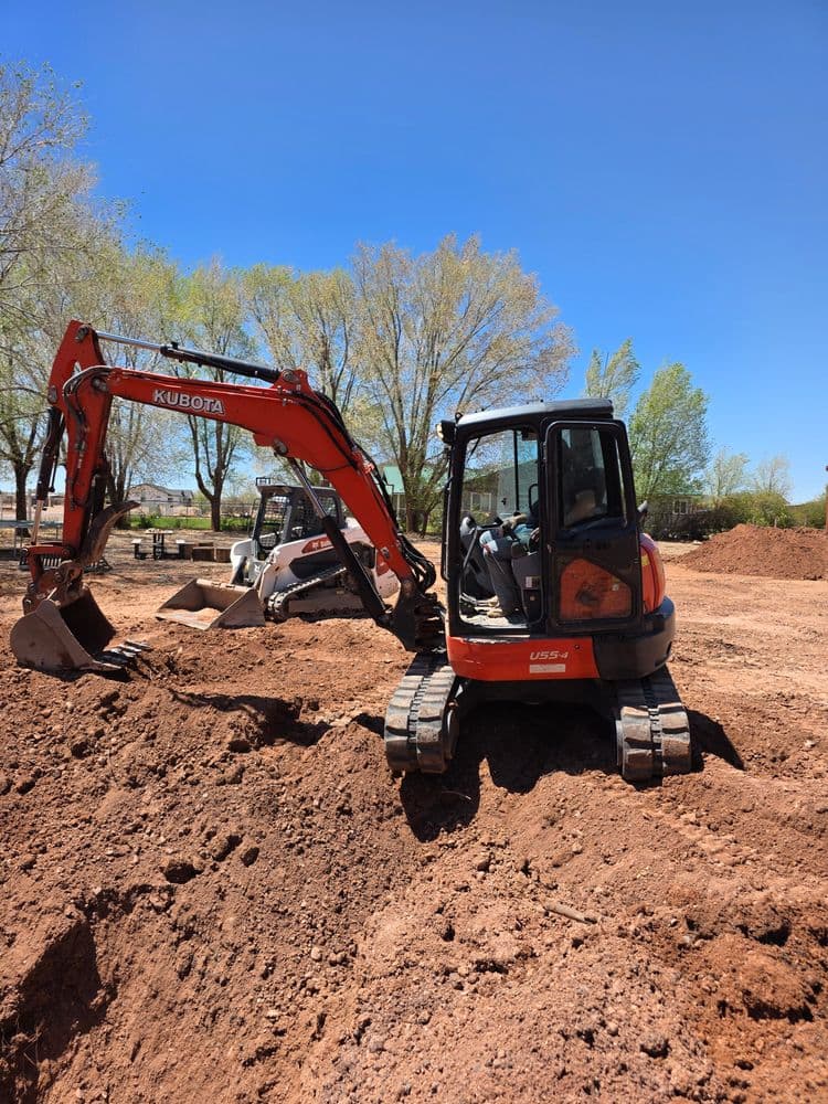 Kubota excavator working on a construction site with trees in the background.